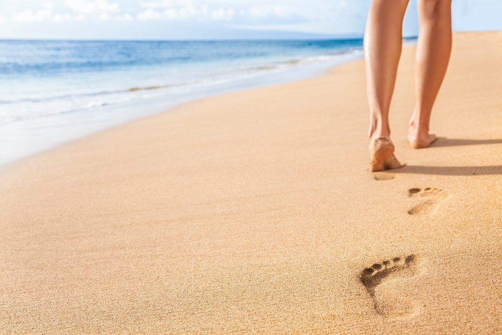 woman walking barefoot on beach
