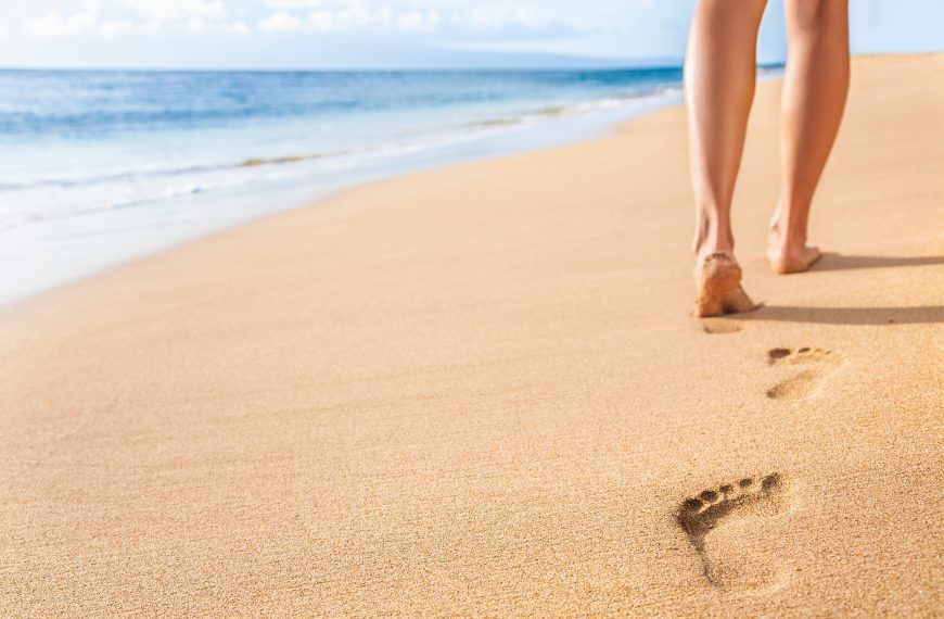 woman walking barefoot on beach