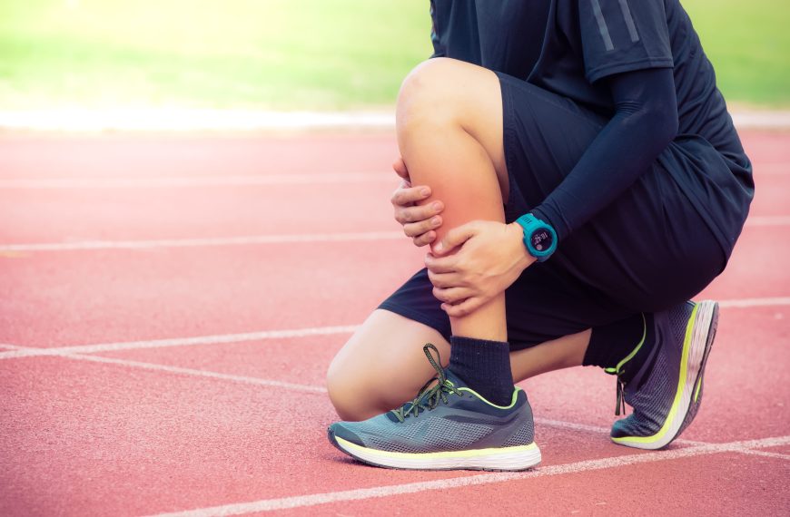 man holding leg on track with shin splint