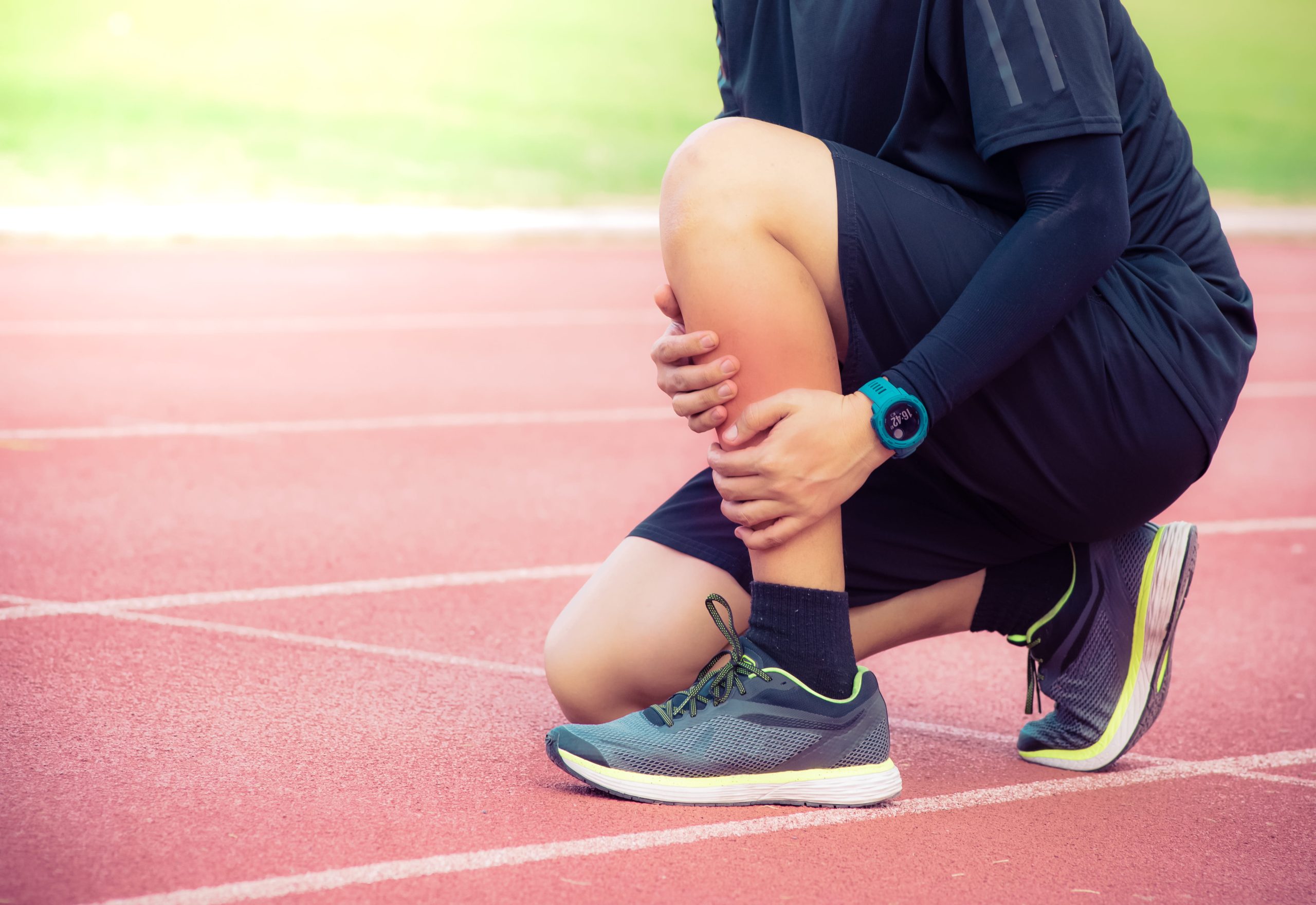 man holding leg on track with shin splint