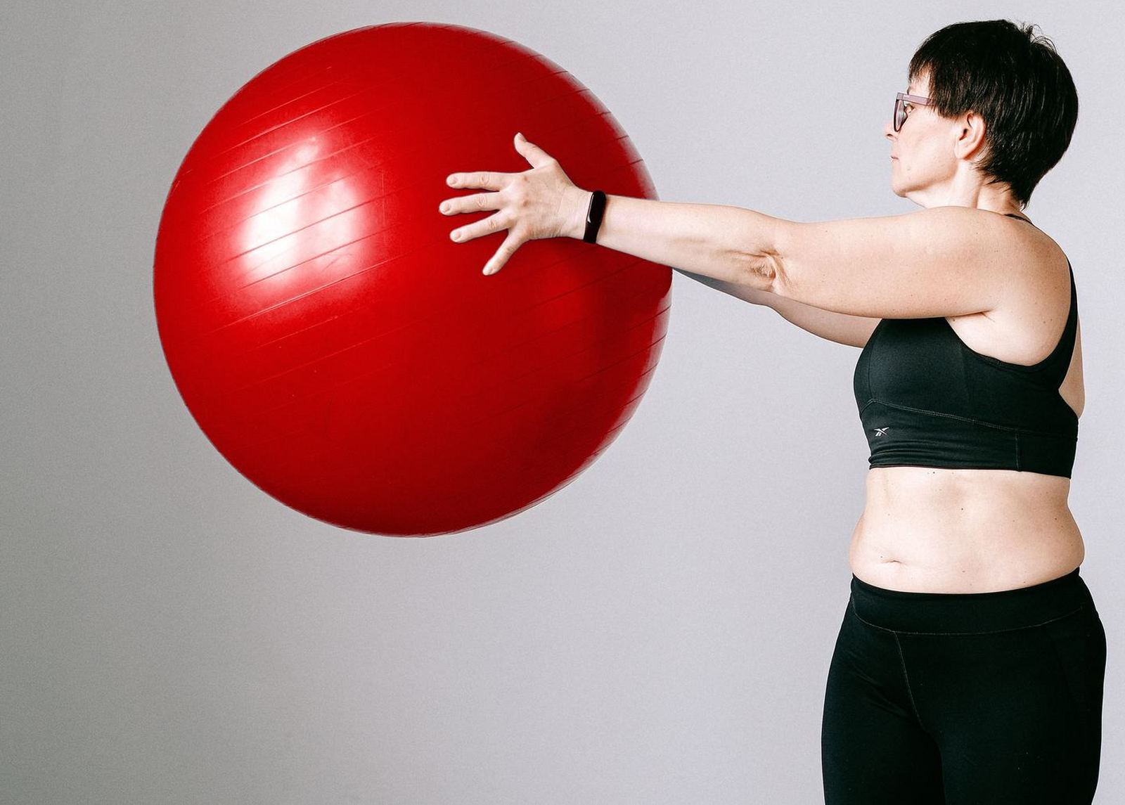 A patient holding an exercise ball out at arm's length